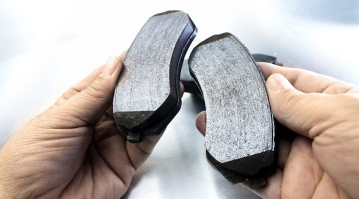 A pair of hands holding a pair of brake pads  Description automatically generated